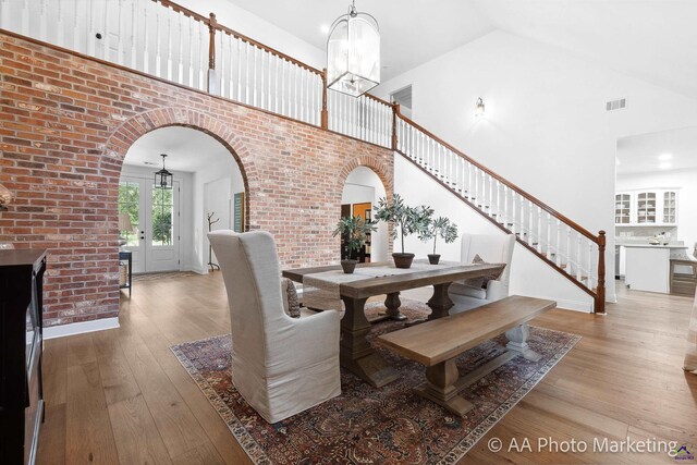 dining space featuring a notable chandelier, light wood-type flooring, and high vaulted ceiling