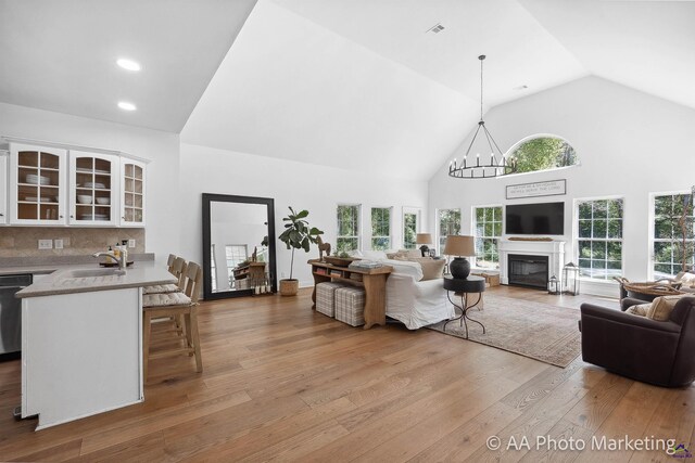 living room featuring light hardwood / wood-style floors, a healthy amount of sunlight, sink, and high vaulted ceiling