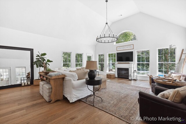 living room featuring hardwood / wood-style flooring, a wealth of natural light, high vaulted ceiling, and an inviting chandelier