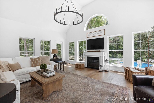 living room featuring wood-type flooring, high vaulted ceiling, and an inviting chandelier