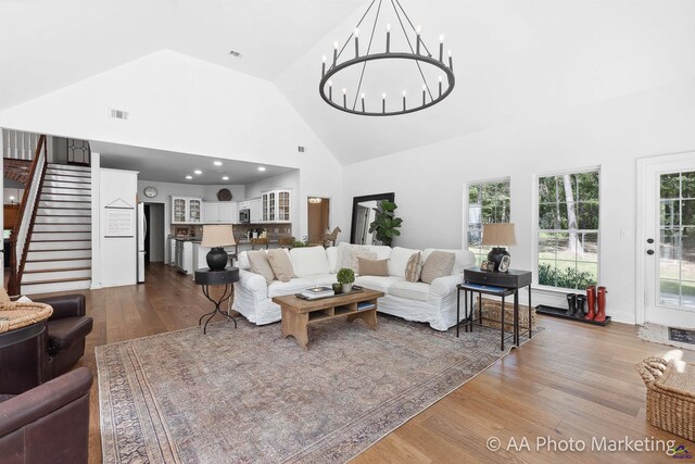 living room featuring hardwood / wood-style floors, high vaulted ceiling, and an inviting chandelier