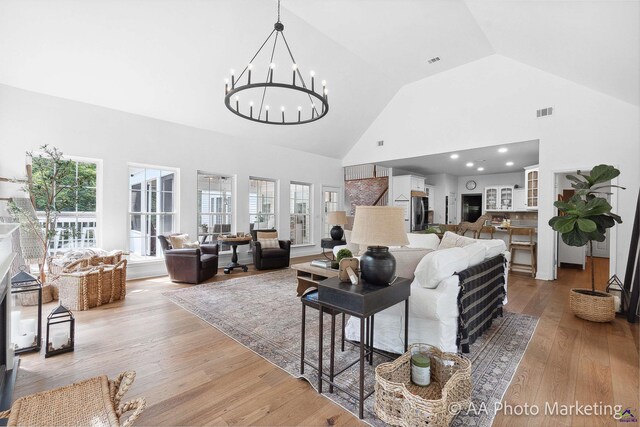 living room featuring a chandelier, light wood-type flooring, and high vaulted ceiling