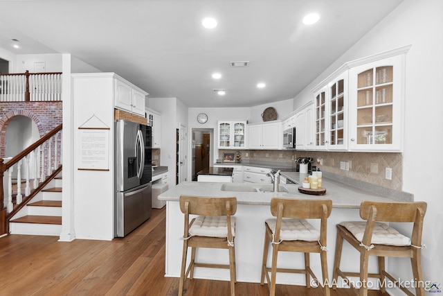 kitchen with white cabinets, backsplash, kitchen peninsula, and stainless steel appliances