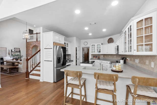 kitchen with stainless steel appliances, kitchen peninsula, a breakfast bar area, decorative backsplash, and white cabinets