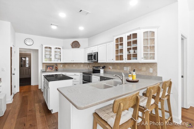 kitchen featuring kitchen peninsula, white cabinetry, decorative backsplash, and appliances with stainless steel finishes