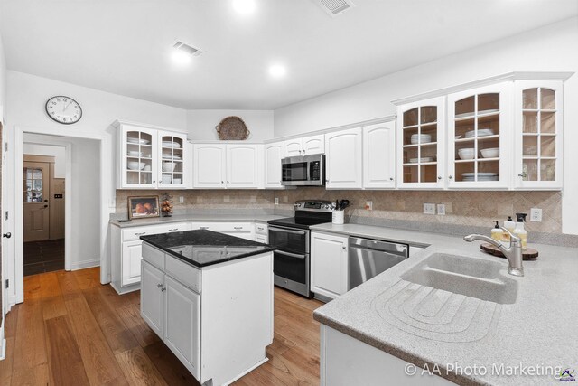 kitchen with white cabinets, decorative backsplash, a center island, and stainless steel appliances