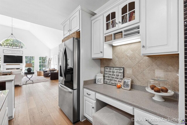 kitchen featuring vaulted ceiling, white cabinetry, light hardwood / wood-style flooring, and stainless steel refrigerator with ice dispenser