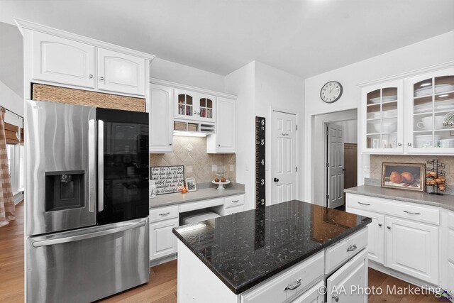 kitchen with tasteful backsplash, dark stone counters, light hardwood / wood-style flooring, stainless steel fridge with ice dispenser, and white cabinetry