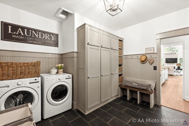 clothes washing area with washer and clothes dryer, wood walls, cabinets, and dark tile patterned flooring