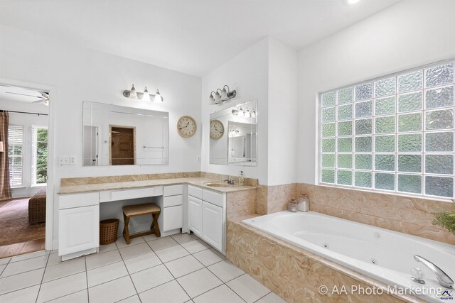 bathroom with tile patterned flooring, vanity, and tiled bath