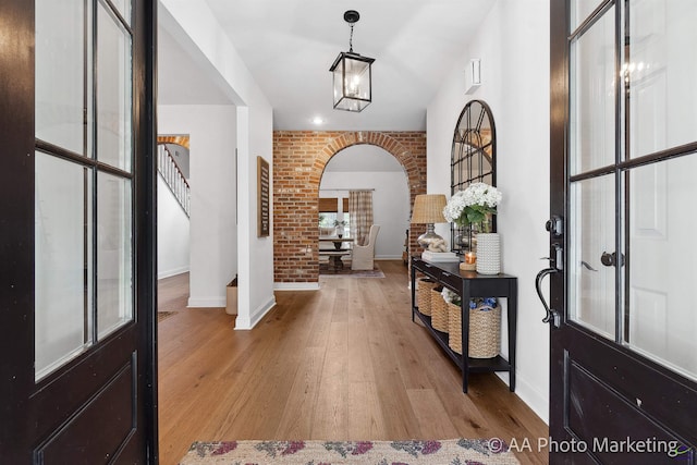 entryway with french doors, light hardwood / wood-style floors, and brick wall