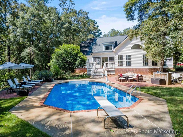 view of pool featuring an outdoor living space, a diving board, a patio, and a wooden deck