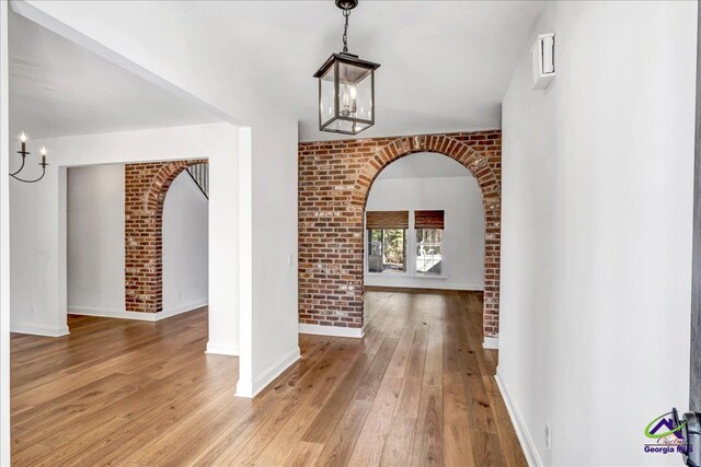 interior space with hardwood / wood-style flooring and brick wall