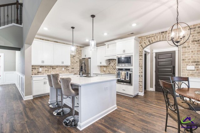 kitchen featuring an island with sink, pendant lighting, white cabinets, and stainless steel appliances