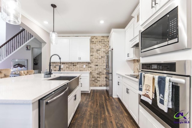 kitchen with pendant lighting, white cabinets, sink, dark hardwood / wood-style floors, and appliances with stainless steel finishes