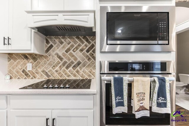 kitchen with white cabinets, appliances with stainless steel finishes, backsplash, and premium range hood