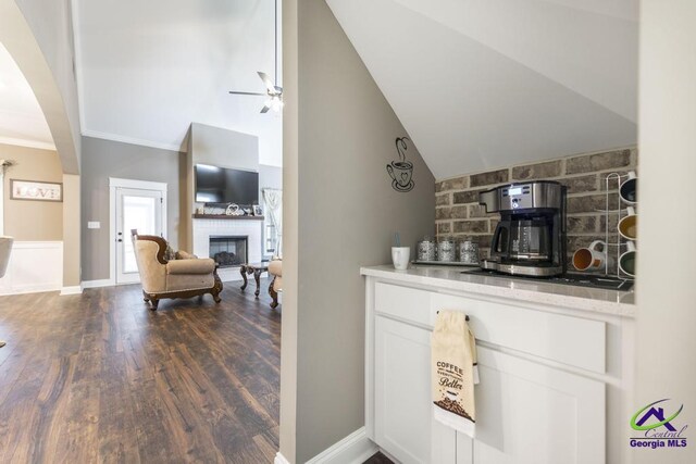 bar featuring a large fireplace, ceiling fan, dark hardwood / wood-style floors, white cabinetry, and lofted ceiling