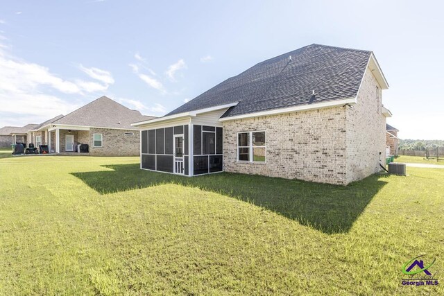 rear view of property with a sunroom, cooling unit, and a yard