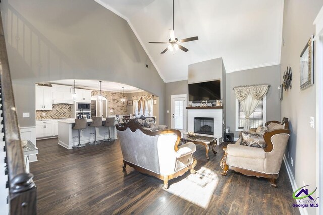 living room featuring ornamental molding, high vaulted ceiling, ceiling fan, and dark wood-type flooring