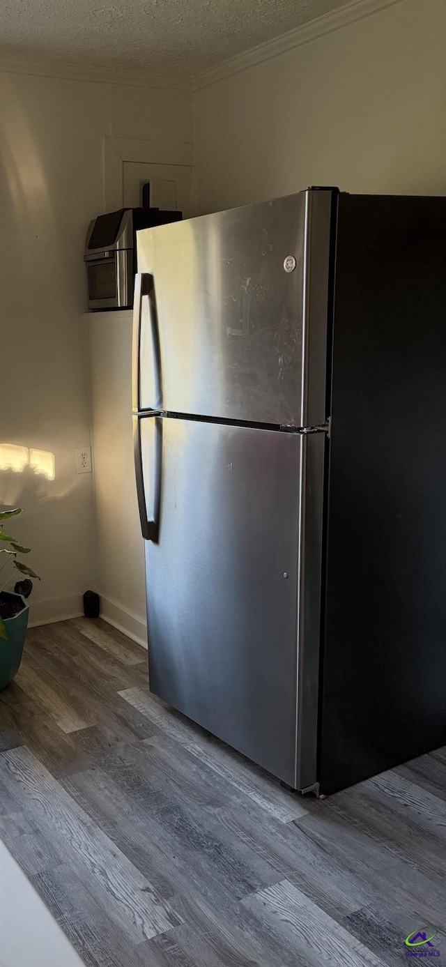 kitchen featuring crown molding, stainless steel fridge, a textured ceiling, and wood-type flooring