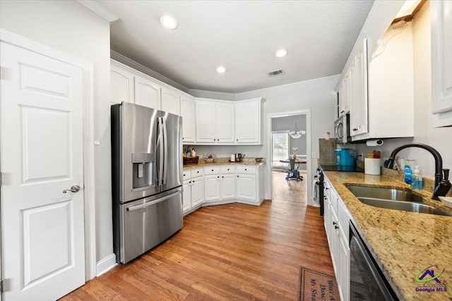 kitchen with light stone countertops, appliances with stainless steel finishes, a textured ceiling, sink, and white cabinets