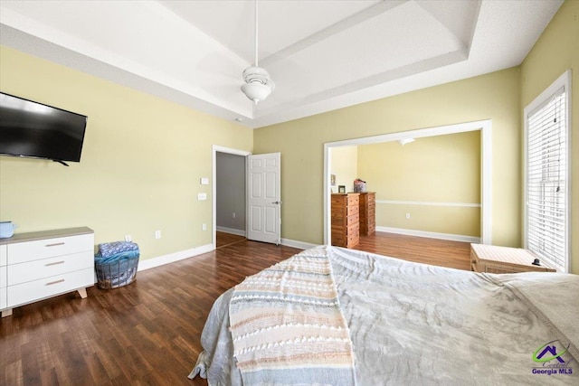 bedroom featuring a raised ceiling, ceiling fan, and dark hardwood / wood-style flooring