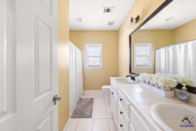 bathroom featuring tile patterned flooring, a textured ceiling, vanity, and a wealth of natural light