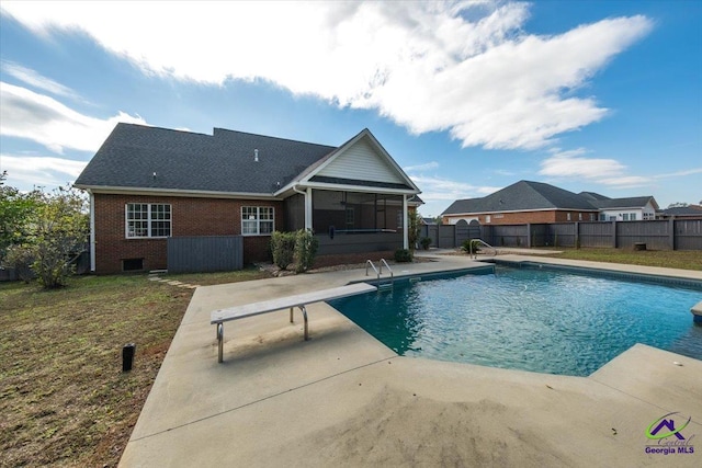 view of pool with a lawn, a sunroom, and a diving board