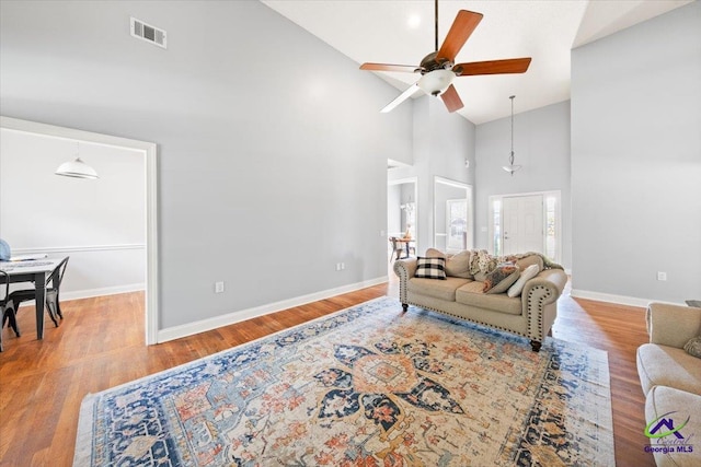 living room with wood-type flooring, high vaulted ceiling, and ceiling fan