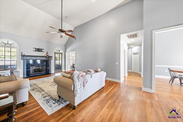 living room with light hardwood / wood-style floors, high vaulted ceiling, plenty of natural light, and ceiling fan