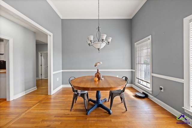 dining room with hardwood / wood-style floors, ornamental molding, and a notable chandelier