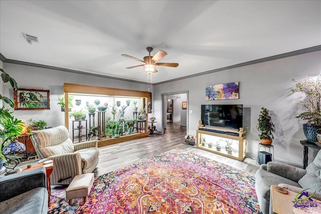 living room with light wood-type flooring, ceiling fan, and crown molding