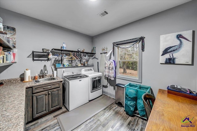 laundry room featuring light hardwood / wood-style floors, sink, cabinets, and independent washer and dryer