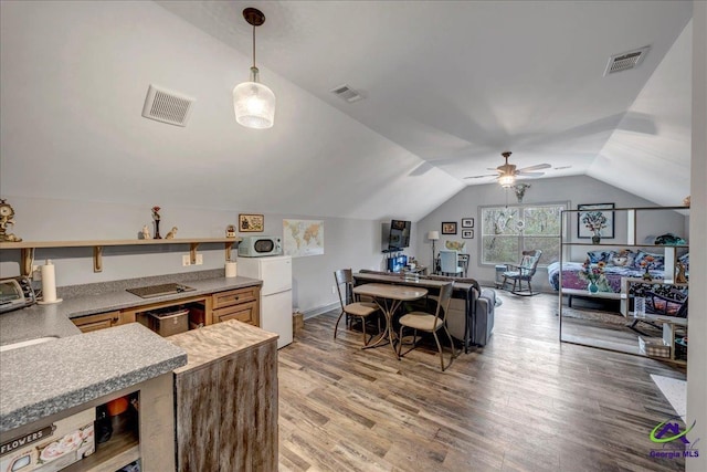 kitchen featuring ceiling fan, kitchen peninsula, white fridge, vaulted ceiling, and hardwood / wood-style flooring