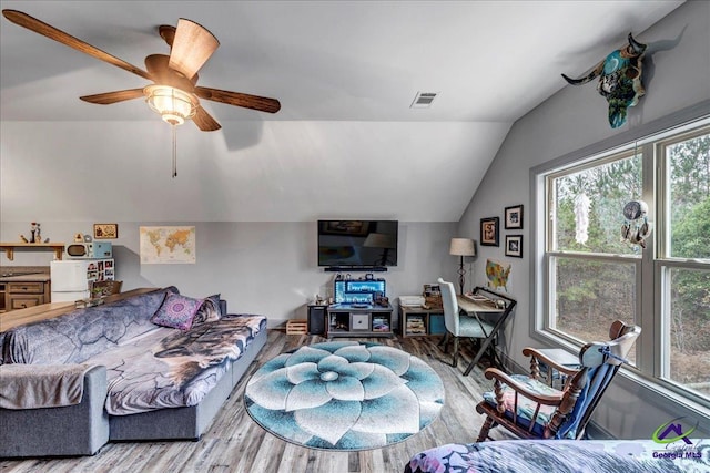 living room with ceiling fan, light hardwood / wood-style floors, and vaulted ceiling