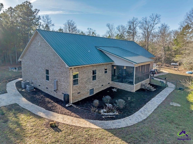 rear view of house featuring central air condition unit, a sunroom, and a yard