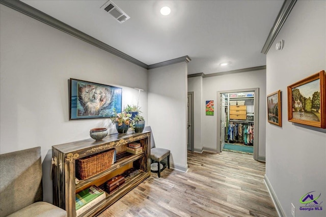 hallway with light wood-type flooring and crown molding