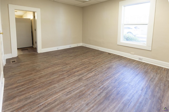 spare room featuring dark hardwood / wood-style floors and a drop ceiling