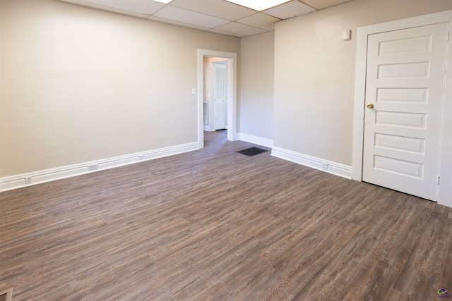 spare room with a paneled ceiling and dark wood-type flooring