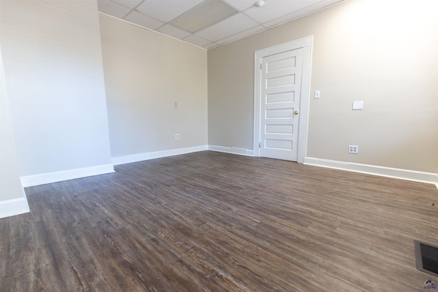 empty room featuring a paneled ceiling and dark hardwood / wood-style flooring