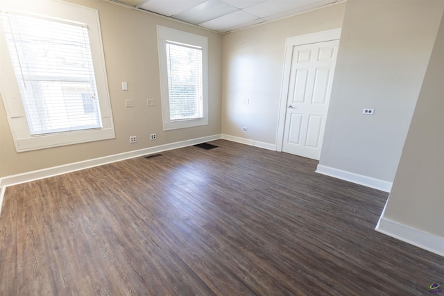 unfurnished room with a drop ceiling and dark wood-type flooring