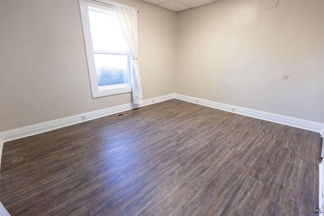 empty room featuring a drop ceiling and dark wood-type flooring