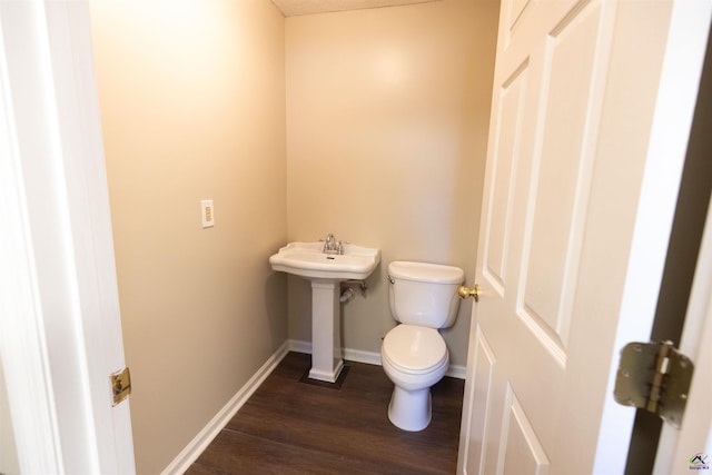 bathroom featuring wood-type flooring, toilet, and sink