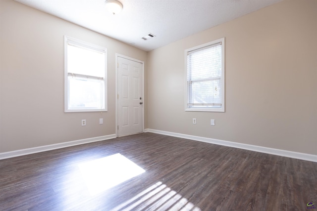 empty room with a textured ceiling and dark hardwood / wood-style floors