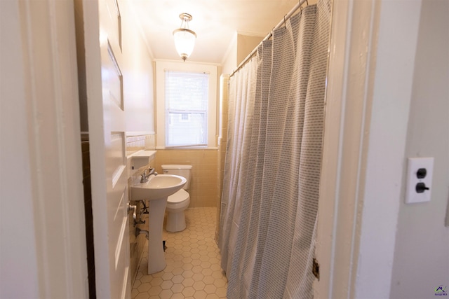 bathroom with toilet, tile walls, ornamental molding, and sink