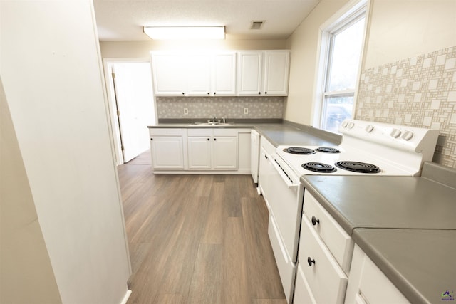 kitchen with white cabinetry, sink, tasteful backsplash, wood-type flooring, and white appliances