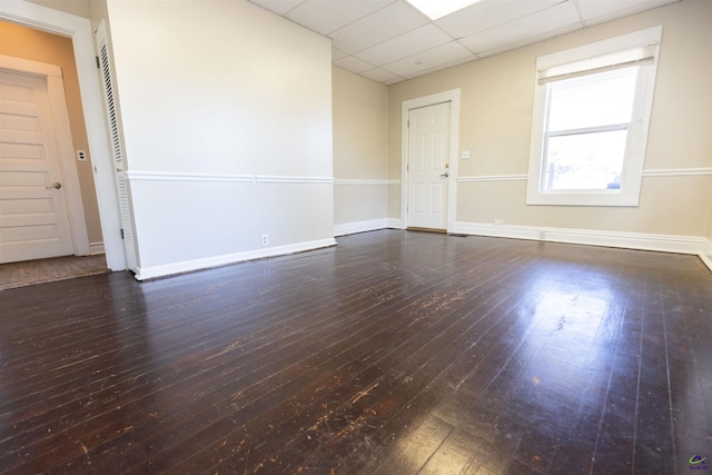 spare room with a paneled ceiling and dark wood-type flooring