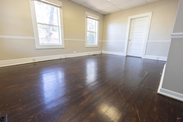 spare room with a paneled ceiling and dark wood-type flooring