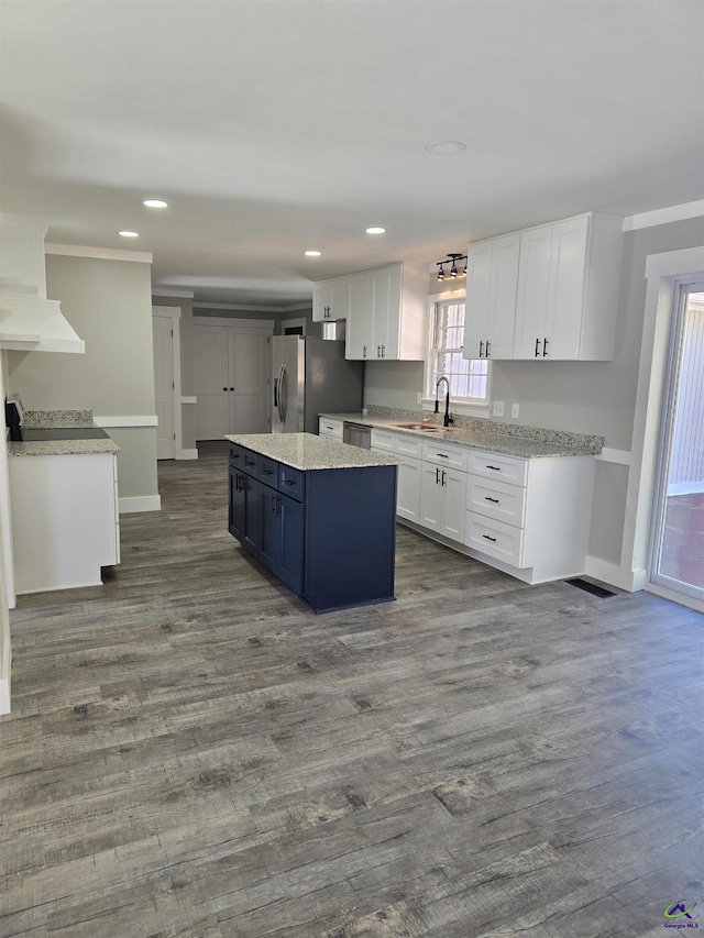 kitchen featuring hardwood / wood-style floors, white cabinets, sink, appliances with stainless steel finishes, and a kitchen island