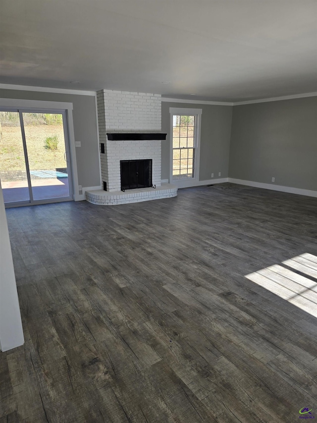 unfurnished living room featuring dark wood-type flooring, crown molding, and a brick fireplace